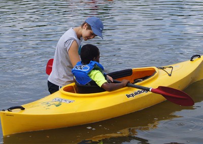 Casey helping a youth at her summer camp experience kayaking for the first time.
